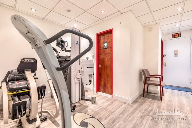 exercise room with a drop ceiling and light wood-type flooring