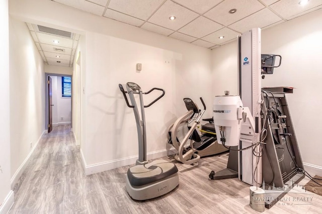 exercise room featuring recessed lighting, a drop ceiling, wood finished floors, and baseboards