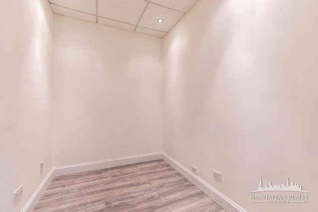 interior space with a paneled ceiling, baseboards, and light wood-type flooring