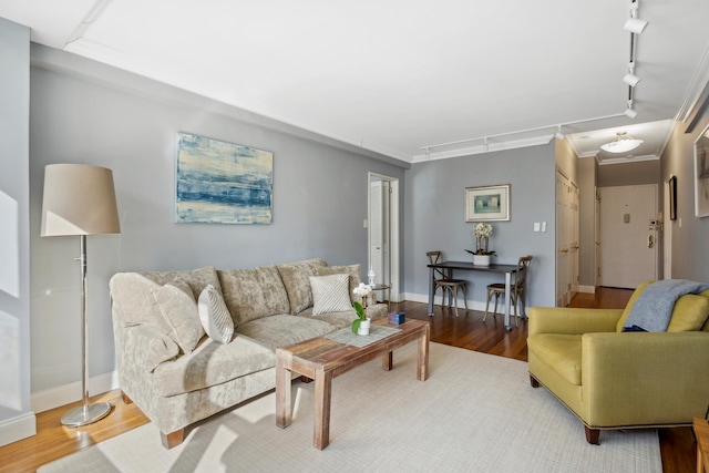 living area with rail lighting, baseboards, ornamental molding, and wood finished floors