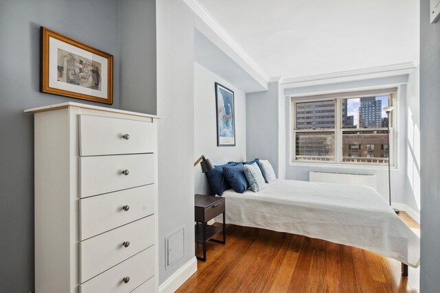 bedroom with crown molding, radiator, and hardwood / wood-style floors