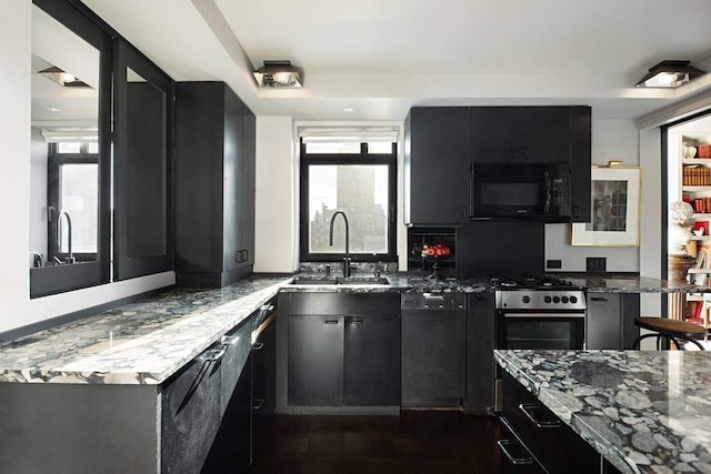 kitchen with black microwave, dishwasher, dark cabinetry, and dark stone countertops