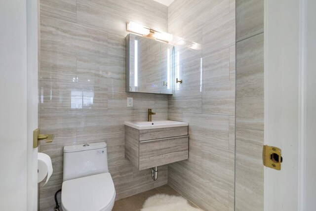 bathroom with tile walls, sink, and toilet