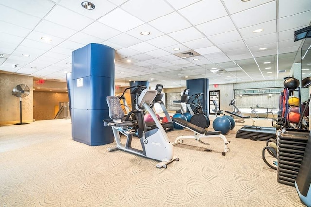 exercise room featuring a paneled ceiling and light colored carpet