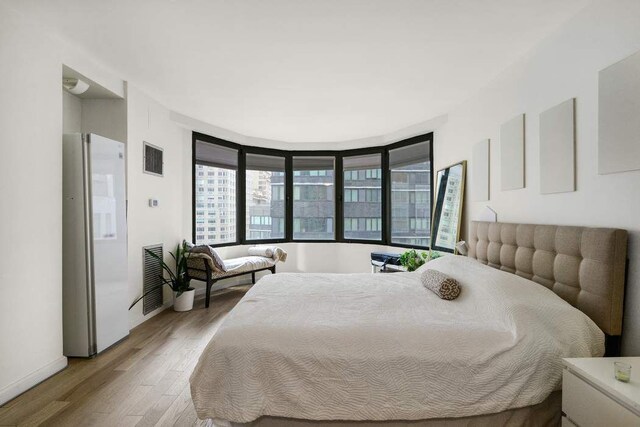 bedroom featuring hardwood / wood-style flooring and white fridge with ice dispenser