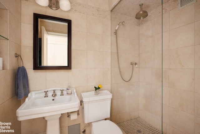 bathroom featuring a tile shower, tile walls, and toilet