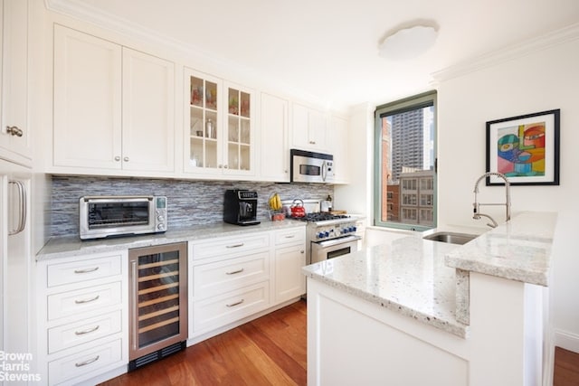 kitchen featuring sink, stainless steel range, beverage cooler, light stone countertops, and white cabinets