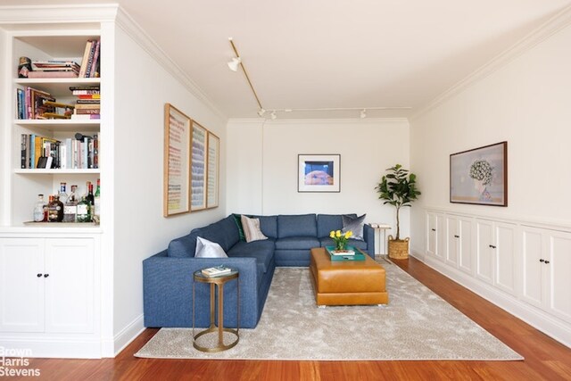 living room featuring crown molding, rail lighting, hardwood / wood-style floors, and built in shelves