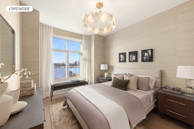 bedroom featuring wood-type flooring, a water view, and a chandelier