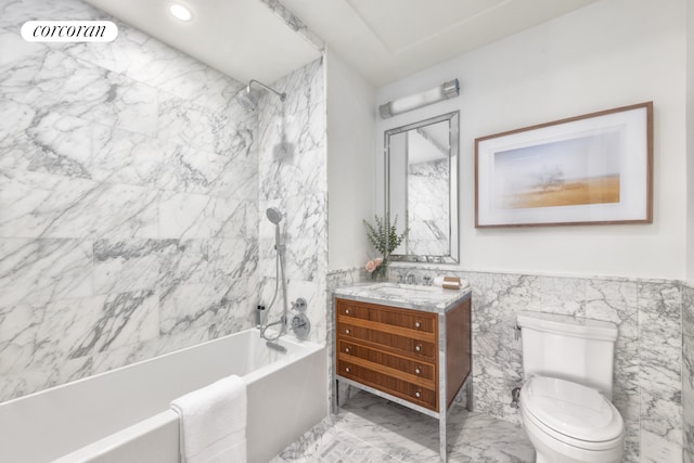 bathroom featuring marble finish floor, tile walls, toilet, vanity, and washtub / shower combination