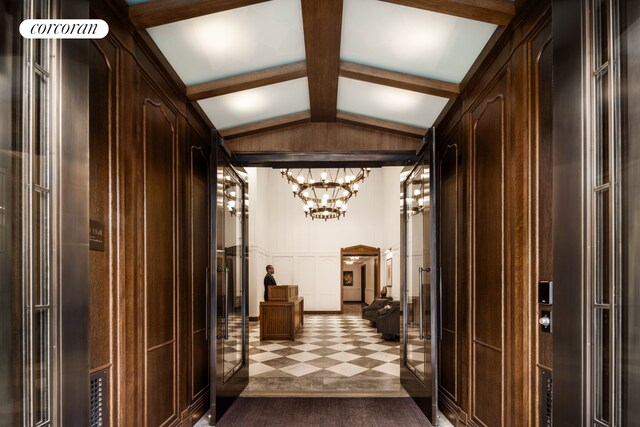 corridor featuring vaulted ceiling with beams, a chandelier, a decorative wall, and tile patterned floors