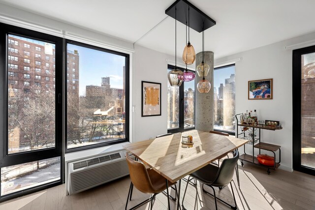 dining area with wood-type flooring and a wall unit AC