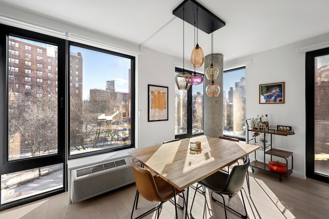 dining space featuring a view of city, wood finished floors, and a healthy amount of sunlight