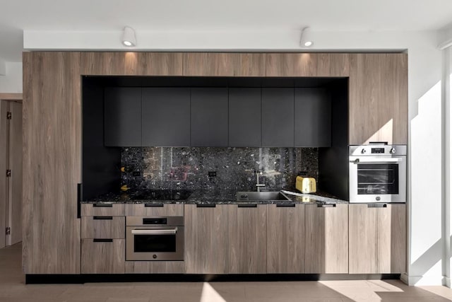 kitchen featuring sink, dark stone countertops, and oven