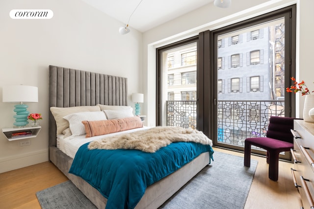 bedroom featuring baseboards, wood finished floors, and access to outside