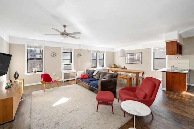 living room featuring dark wood-style floors, cooling unit, radiator, baseboards, and ceiling fan