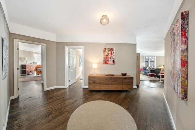 corridor featuring dark wood-type flooring and baseboards