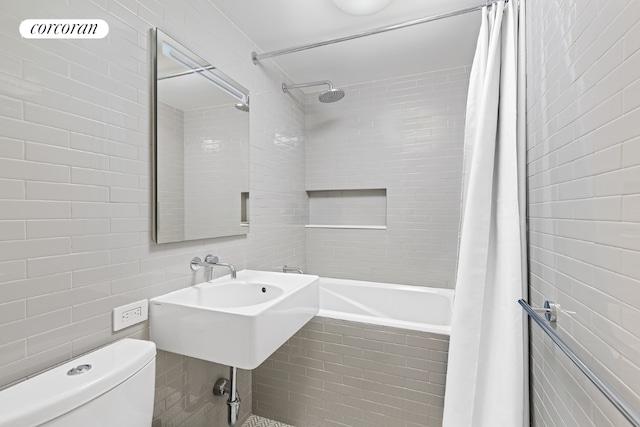 bathroom with tile walls, shower / bath combination with curtain, and toilet