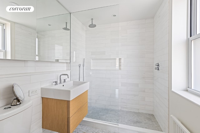 bathroom featuring plenty of natural light, toilet, and tiled shower