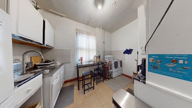 kitchen featuring a sink, baseboards, white appliances, and white cabinets