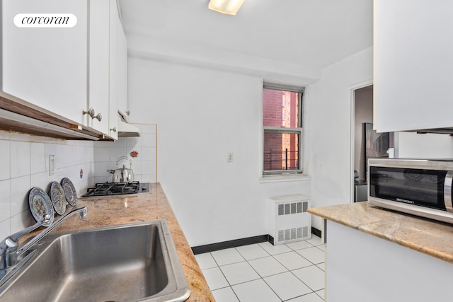 kitchen featuring light tile patterned floors, stainless steel appliances, radiator, decorative backsplash, and a sink