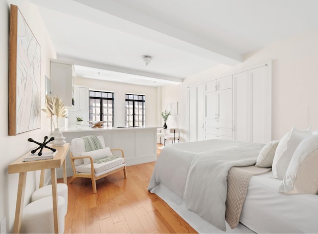 bedroom featuring baseboards, beamed ceiling, and light wood finished floors