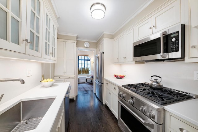 kitchen with white cabinetry, stainless steel appliances, sink, dark wood-type flooring, and crown molding