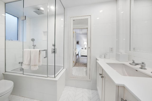 full bathroom featuring toilet, combined bath / shower with glass door, and vanity