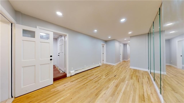 basement featuring a baseboard heating unit, recessed lighting, baseboards, and light wood finished floors