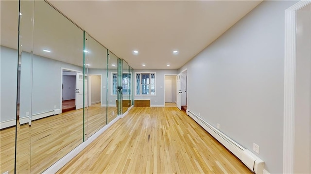 interior space featuring recessed lighting, a baseboard heating unit, baseboards, and light wood-style floors