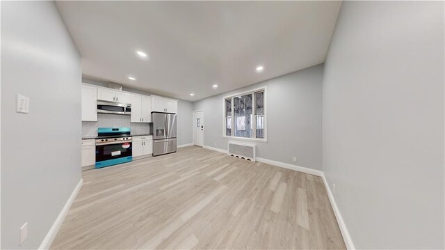 kitchen with white cabinetry, tasteful backsplash, light hardwood / wood-style flooring, radiator, and stainless steel appliances