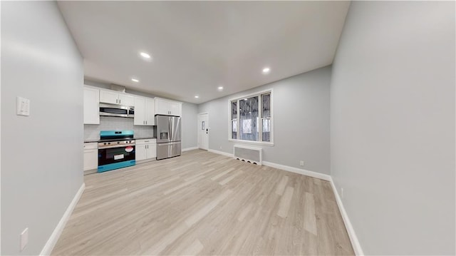 kitchen featuring light wood-style flooring, tasteful backsplash, stainless steel appliances, white cabinets, and baseboards