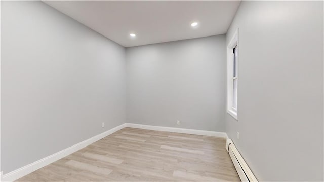 empty room featuring recessed lighting, light wood-style flooring, a baseboard heating unit, and baseboards