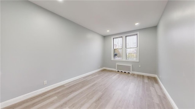 spare room featuring recessed lighting, radiator, light wood-type flooring, and baseboards