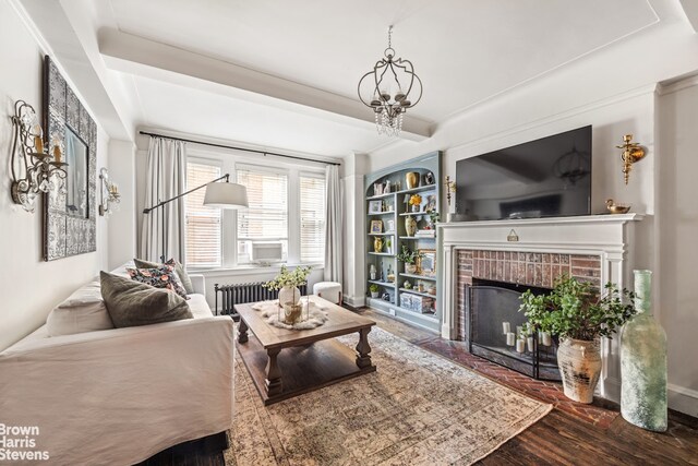 living room with radiator, built in features, dark hardwood / wood-style floors, a fireplace, and beamed ceiling