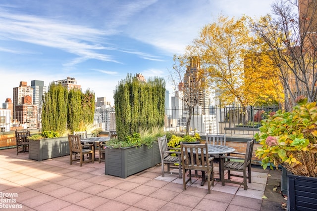 view of patio / terrace with outdoor dining area, a view of city, and fence