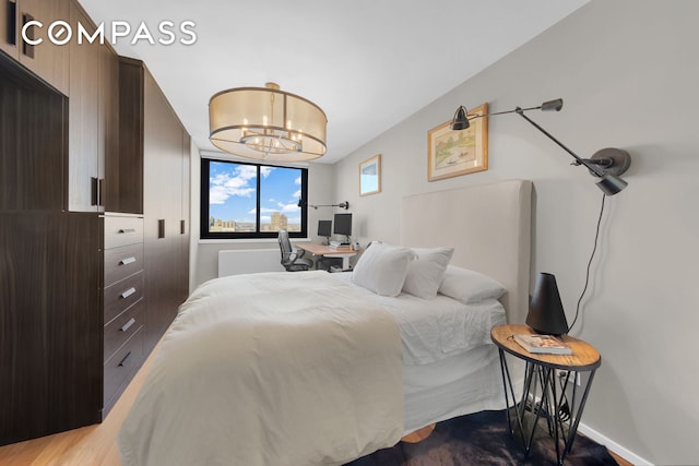 bedroom with baseboards, a notable chandelier, and wood finished floors