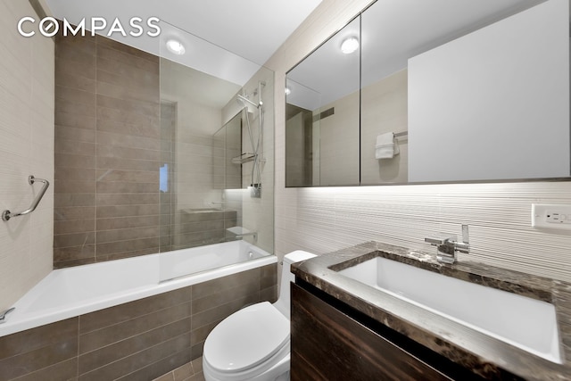 bathroom featuring vanity, visible vents, tiled shower / bath combo, tile walls, and toilet