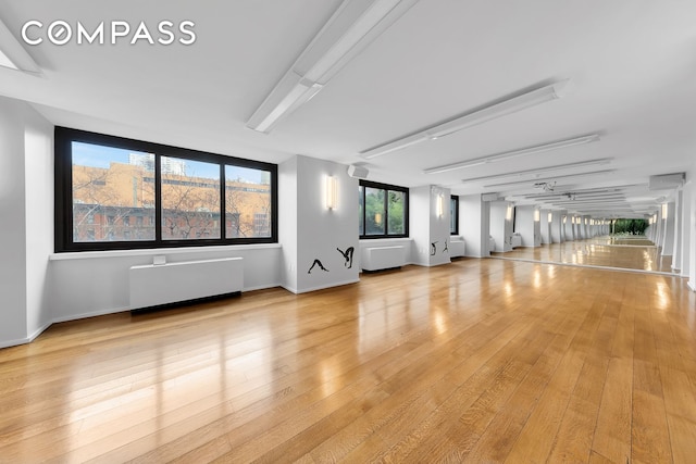 empty room with light wood-style floors, baseboards, and radiator