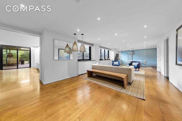 living area featuring recessed lighting, baseboards, and light wood-style floors