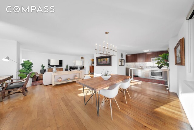 dining space featuring light wood-type flooring and a notable chandelier