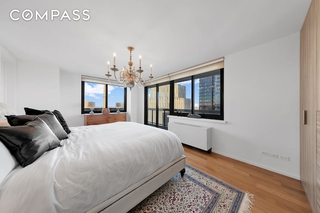 bedroom featuring baseboards, radiator heating unit, an inviting chandelier, and wood finished floors