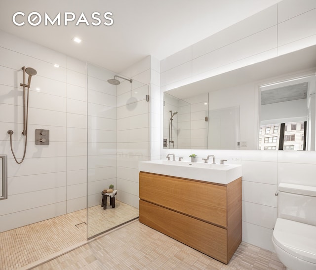 bathroom featuring tile walls, toilet, tiled shower, and vanity