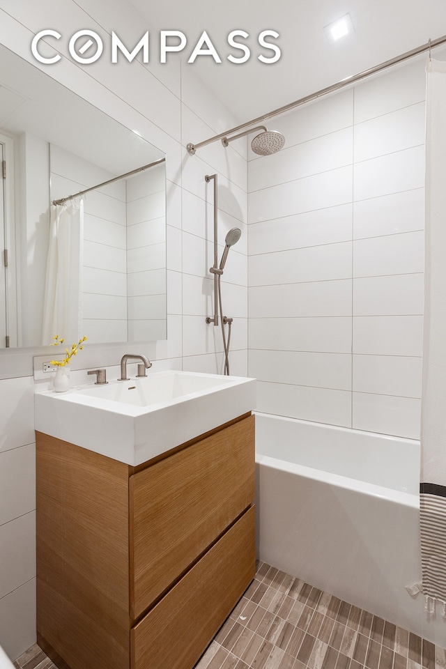 full bath with vanity, tile walls, and shower / tub combo