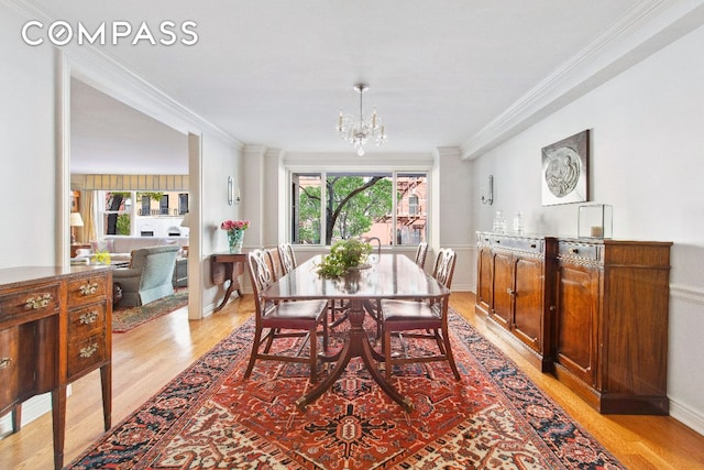 dining room with ornamental molding, an inviting chandelier, and light wood-type flooring