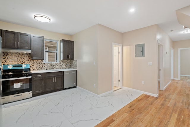 kitchen with under cabinet range hood, electric panel, decorative backsplash, appliances with stainless steel finishes, and a sink