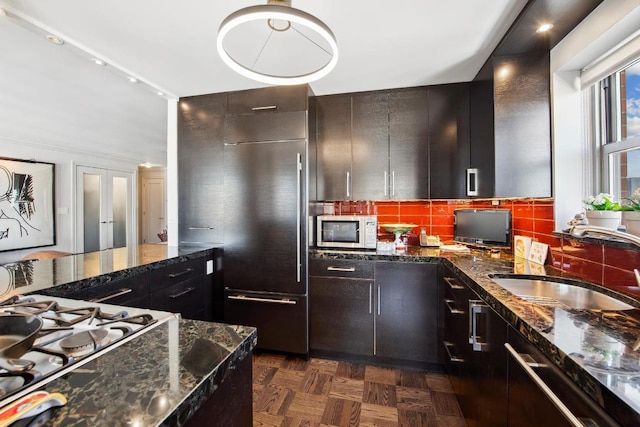 kitchen with french doors, dark parquet flooring, stovetop, sink, and tasteful backsplash