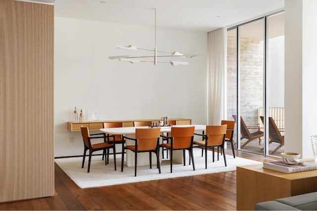 dining space with hardwood / wood-style flooring, a notable chandelier, and a wall of windows