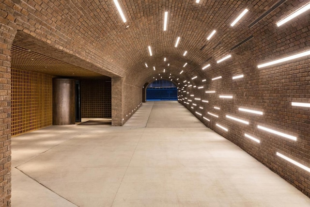 interior space featuring lofted ceiling, brick wall, concrete flooring, and brick ceiling