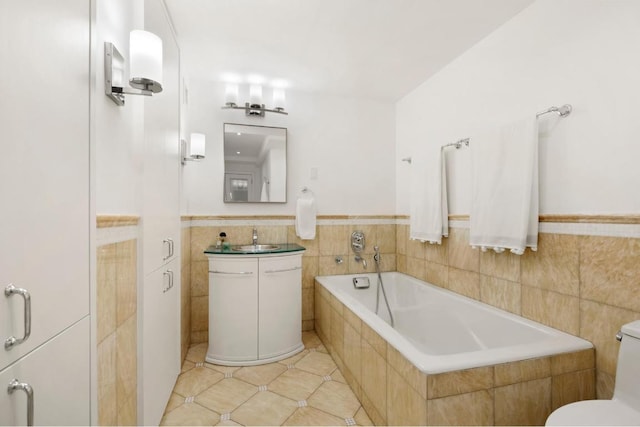 bathroom with vanity, tile patterned flooring, tile walls, and tiled tub